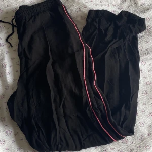 Byxor - Ett par fina o sköna byxor med en rosa kant på sidan av benen som är en snygg detalj!🩷 Tunt o luftigt material🌷✨ Dom är inte vida nertill. Man kan knyta i midjan! Inga synliga defekter!!Skriv till mig om du undrar nåt!🫶