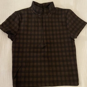 Rutig topp - Väldigt fin rutig topp med skön krage som är justerbar med dragkedja 