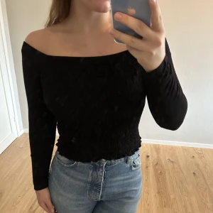 Topp - Off-shoulder-tröja med smockad mittdel. Ärmarna är i vanligt bomulls-tyg.