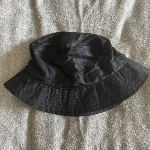 Svart fiskehatt  - Fiskehatt i glansigt material. Från Gina Tricot. Fint skick. 