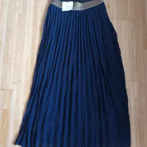 Säljer  long oanvänd plisserad kjolar en i mörk blue 