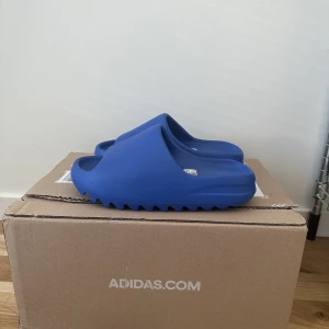 Yeezy Slide Azure - Säljer mina yeezy slide strl 38, helt oanvända och boxen finns kvar 🫧 obs dom är ganska små i storleken! 