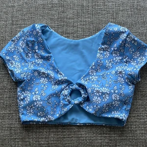 Söt bikini topp! - Jättefin blå bikinitopp med blommigt mönster. Perfekt för dem som vill ha coverage för axlarna☺️Det är padding i toppen så man behöver inte ha något under🙌 (Aldrig använt då den är för liten för mig)