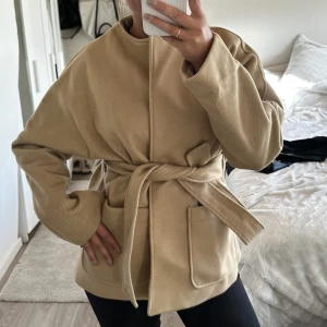 BEIGE KORT KAPPA - beige kort kappa med band, helt ny