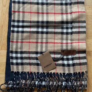 Burberry Halsduk - Oanvänd Kashmir Burberry halsduk i tartanmönster. I tunnare kvalitet.  Längd 180 cm, bredd 30 cm. 