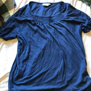 En fin marinblå t-shirt/blus med lite detaljer vid bröstet. Lite tajtare vid armarna.