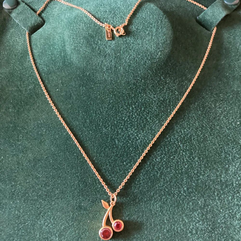 Halsbandet med två röda körsbär från Maria Nilsdotter äkta silver guldpläterat.  Asken ingår inte . Accessoarer.