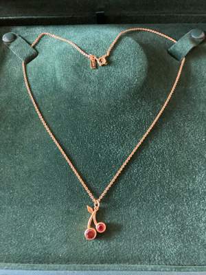 Halsbandet med två röda körsbär från Maria Nilsdotter äkta silver guldpläterat.  Asken ingår inte 