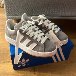 Adidas campus 00s - Säljer ett par Adidas campus 00s i grå. Skorna är aldrig använda därav är de i prima skick. Skorna är i 35.5 men skulle själv säga att de även passar 36. Både Låda och kvitto finns