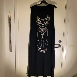 Mysklänning - En svart mysklänning med kattmotiv  Beställd online så storleken som står är inte riktigt den som gäller. Storleken är ca M/L