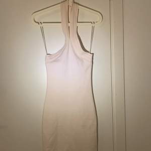 En vit, kort halterneckklänning 💕 Säljer då den inte kommer till användning. ☺️Köpt från Gina tricot, i storlek xs 🫶🏻Knappfäste runt nacken. Har du frågor eller är intresserad, skriv!😚