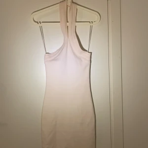 Vit halterneckklänning - En vit, kort halterneckklänning 💕 Säljer då den inte kommer till användning. ☺️Köpt från Gina tricot, i storlek xs 🫶🏻Knappfäste runt nacken. Har du frågor eller är intresserad, skriv!😚