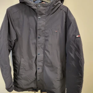 Jacka Tommy Hilfiger strl 176 - Mörkblå lätt fodrad jacka från Tommy Hilfiger. Knappt använd. I strl 176