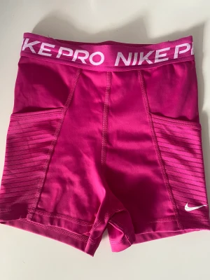 Nike pro shorts Dri-fit - Rosa Nike pro shorts med fickor på sidorna. På baksidan av shortsen finns även en ficka med dragkedja.