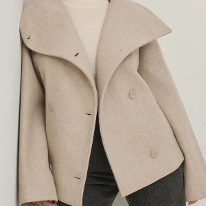 Kort beige kappa💕 - Säljer den här snygga kappan som är helt slutsåld!💞💘Är nästan identiskt med den slutsålda och populära NA-KD kappan💗Aldrig använd och har inga defekter🫶🏼 Säljer då jag har två exemplar💓 Använd gärna köp nu funktionen🥰❤️Pris kan alltid diskuteras💕💕