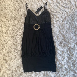 Klänning  - Svart klänning med silver detalj.  Aldrig använd och är i nyskick. Är i storlek M/L men passar även Xs/S då den är väldigt stretchig. 