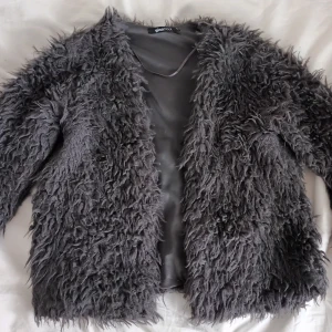 Grå pälsjacka - Mycket bra skick! Material: Polyester, fuskpäls  Möjligt att få till billigare frakt om du köper privat och inte via Plick. Hör av dig så kan vi ordna det. 