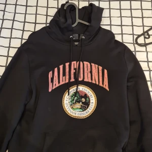 Svart hoodie  - Svart hoodie med tryck på bröstet. 