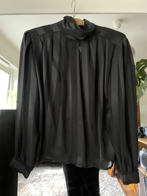 Semi Transparent Blus - Denna grå-blåa blus från Beyond Retro behöver en ny garderob nu. Superfin till ett par höga bycor då den ramar in överkroppen väldigt fint. Knäppning i ryggen, och vadderade axlar. Har alltid burit den till höga utsvängda jeans. 