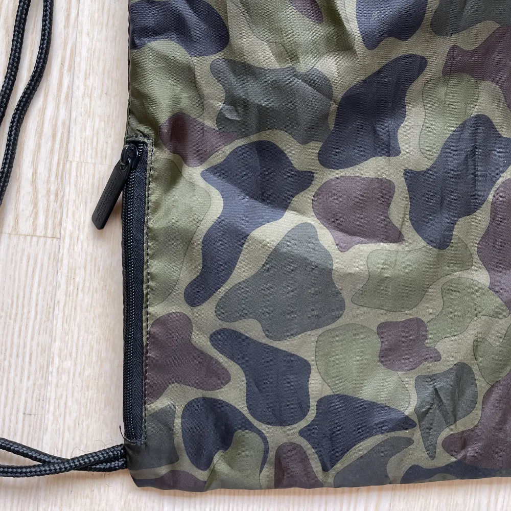 Gympapåse från Adidas i militärmönster. Använd fåtal gånger. Ficka med dragkedja på sidan. Mått: 37 x 46 cm. Väskor.