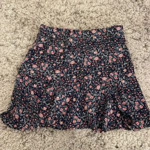 Kjol - En jättefin mörkblå kjol med blommor, helt oanvänd från Cubus. Strl 34 ung XS/S! Säljer pga att den inte passar! 