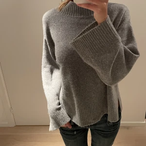 Stickad tröja  - Grå stickad tröja från Pull & Bear. Otroligt mjuk i material och är i super bra skick. Ärmen blir vidare desto längre ner den faller och så finns det en slitt på båda sidorna av tröjan (se bild 3). Skriv om du har några frågor☺️