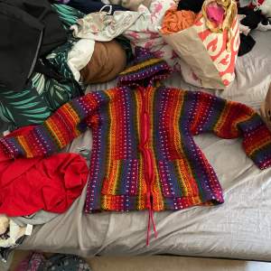 En stickad regnbågs tröja som är gjord utav alpacka ull ifrån Peru 