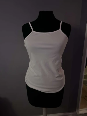 Ett nätt vitt linne  - Ett lite genomskinligt vitt linne, hög framsida och låg baksida.