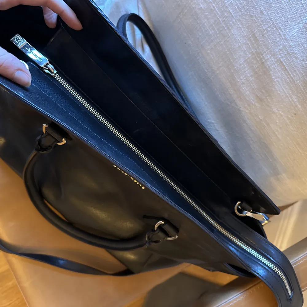 Superfin svart skinnväska från italienska Coccinelle. Perfekt jobbväska med plats för laptop!  Tre innerfack och avtagbar axelrem.   H 29 cm B 33 cm  D 11 cm . Väskor.