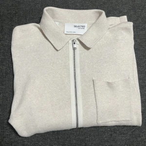 Kofta/overshirt - Beige kofta/overshirt med dragkedja i storlek M från Selected Homme. Använd fåtal tillfällen och i mycket bra skick! 