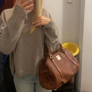 Brun väska med guld detaljer - Säljer denna superfina bruna fiorelli väskan med gulddetaljer som jag köpte för 800kr. Den är i utmärkt skick och har endast använts några gånger. Säljer väskan då jag har många andra och denna inte kommit till så stor användning.