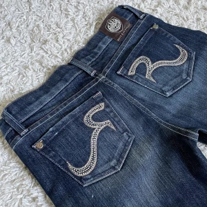 Vintage Rock & Republic jeans - Från märket som gjorde Victoria Beckham jeansen. ❤️ Lågmidjad och bootcut modell, har strass på fickorna och ascool tag. 🫶 Innerben: 88cm, midja rakt över: 36cm. Är 165cm, kan fixa fler mått. 🥰 Håll koll på min profil, säljer för det mesta vintage jeans! 😍