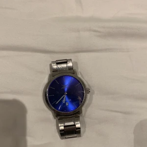 Gul klocka  - Rikrigt snygg klocka från märket Gul. Snygg blå ur tavla. Skickar med extra länkar så att man kan ändra storlek på klockarmbandet