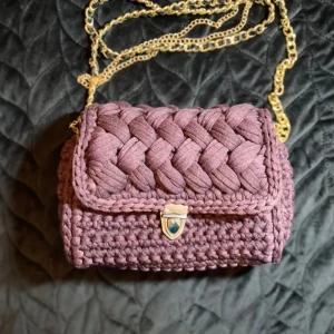 Halvflätad väska - Halvflätad virkad väska i en djupt lila färg. Virkad på bomullsgarn från modeindustrins rester♻️. Har både guldiga och silvriga detaljer.  Mått: längd: 22,5cm Höjd:16cm Djup:6cm  Pris: 700kr+porto