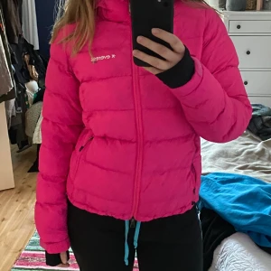 Rosa jacka Everest - Rosa skidjacka från Everest med luva. Har fått en liten skråma som lätt kan sys ihop. 