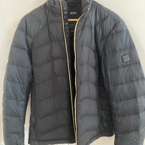 Hugo Boss Jacka  - Säljer min Hugo Boss jacka i storlek M. Det är en dunjacka som fungerar under hela året. Den är i väldigt fint skick och jag säljer den för att den har blivit för liten för mig. Äkta.