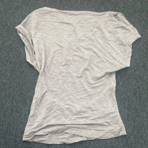 En grå t-shirt som e öppen i ryggen - Den är grå och ett najs material 