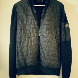 J Lindeberg Hybrid jacka knitted - Säljer en mörkblå knitted hybridjacka från J Lindeberg. Storlek small. I fint skick. Nypris 3200. 