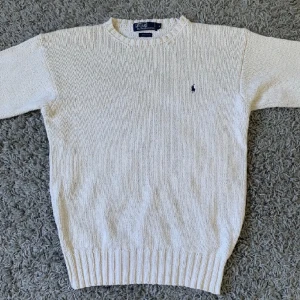 Stickad Ralph Lauren tröja - En fin krämvit stickad Ralph Lauren tröja. Den är varm och passar perfekt nu till vintern men passar även bra till våren och hösten. Använd fåtal gånger, 10/10 skick. Nypris: 2000 kr