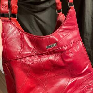 Röd väska med fina detaljer och långa axelband 
