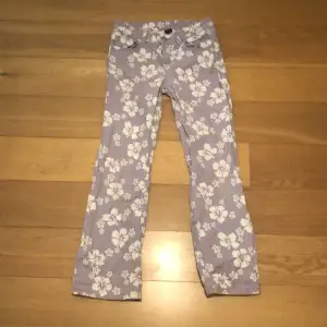 Snygga lågmidjade bootcut jeans i lila med vita blommor på! Jätte bekväma jeans och väl använda men finns ingen slithet elelr skador på dem!