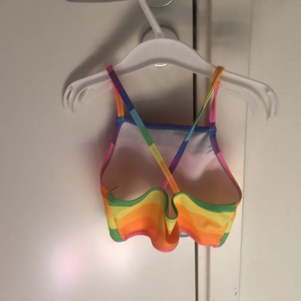 Detta är en regnbåging bikini där över delen är lite längre en vanliga bikinis. På baksidan av överdelen går det en kors över ryggen. Den är använd ca 1/2 gånger. Övrigt.