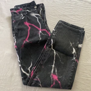 Svarta jeans med imitation av blixtrar - Svart jeans me imitation av blixtrar i vitt och rosa. Strl S. Från shein. Aldrig använda.