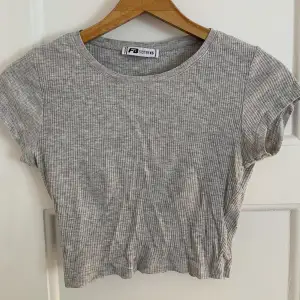Säljer denna gråa kroppade t-shirten som är i ett ribbat material. Storlek xs men skulle säga att den passar en storlek s också.