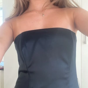 Svart knälång sidenklänning - Såå vacker axelbandslös midi klänning i svart silkesliknande tyg🤍skulle uppskatta att storleken är xs/s💓 klänningen går över knäna på mig som är 165💌 fantastiskt bra skick⭐️säljer då den inte kommer till användning❤️