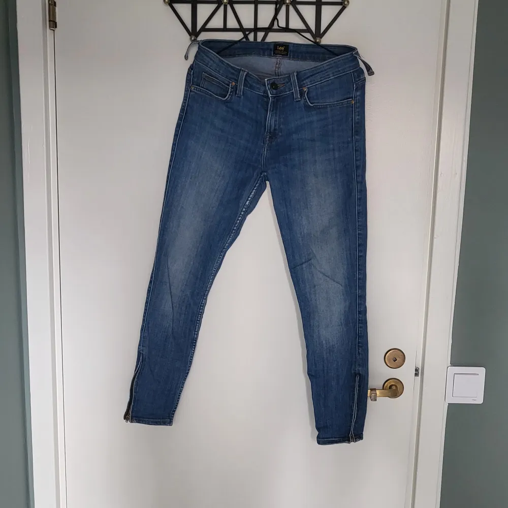 Blå jeans från Lee modell Scarlett cropped, W27/L31. Dekorativ dragkedja i benslut, 2 st hällor lösa se bild, ankellånga. Jeans & Byxor.