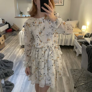 Blommig klänning  - Jätte fin sommarklänning i vit med blåa och gula blommor. Är i mycket bra skick.