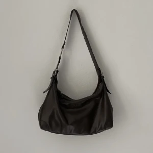 Mörkbrun väska - Superfin mörkbrun handväska i vintage/retro. Säljer då den inte kommer t användning. Skriv vid frågor eller om du vill ha fler bilder! Rymlig och perfekt storlek till vardags. Köp direkt: 500kr Mått: djup: 11 cm, höjd: 20 cm, bredd: 34cm