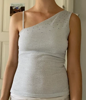 Glittrig topp - Silverglittrig topp i äkta y2k-stil. Gissar på att toppen är köpt på 90-talet/2000-talet från Gina tricit. Även om det står på lappen att toppen är i storlek M uppskattar jag den mer som en S.