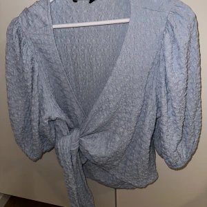 Ljusblå topp - Aldrig använd, bara testad & bortklippta lappar. Ljusblå söt topp med knytning i midjan och puffiga ärmar. Strl L (true to size)